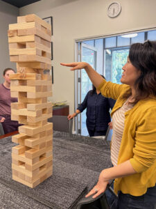 A woman holds her hand out parallel to the Jenga tower