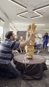 A man crouches as he fails to keep the Jenga tower from falling
