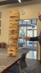 A man tries to flick a block out from the Jenga tower, leading to it crashing