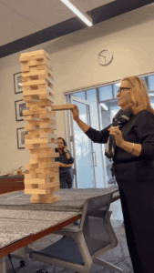 A woman successfully pulls a block from the Jenga tower