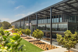 Exterior view of a life science research building with expansive windows, a solar PV panel canopy, and green space