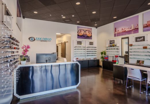 FPBA-designed reception and eyewear display area at San Diego Optometry's Carmel Mountain office in San Diego, CA, featuring a custom barn door and glass display shelving.