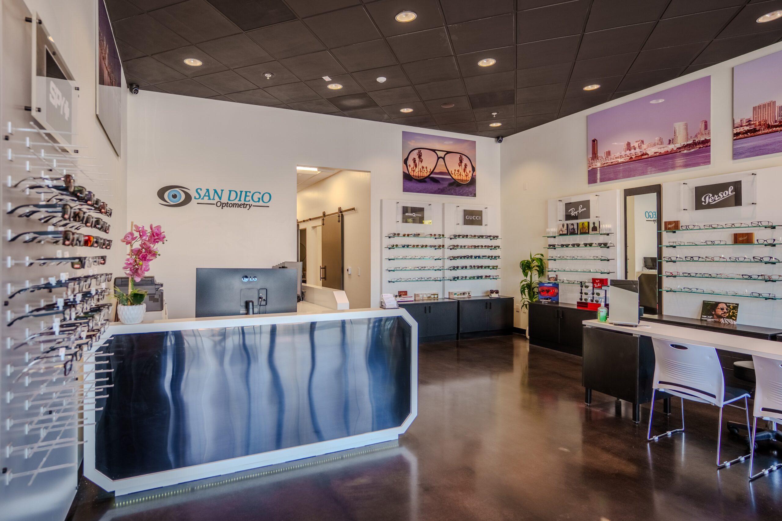 FPBA-designed reception and eyewear display area at San Diego Optometry's Carmel Mountain office in San Diego, CA, featuring a custom barn door and glass display shelving.