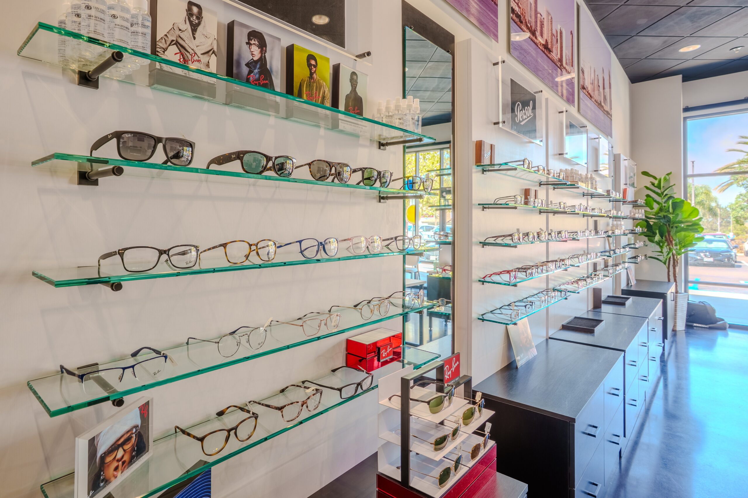 Eyewear display wall at San Diego Optometry, a tenant improvement project by FPBA in San Diego, CA, featuring glass shelving with designer frame and sunglasses displays.