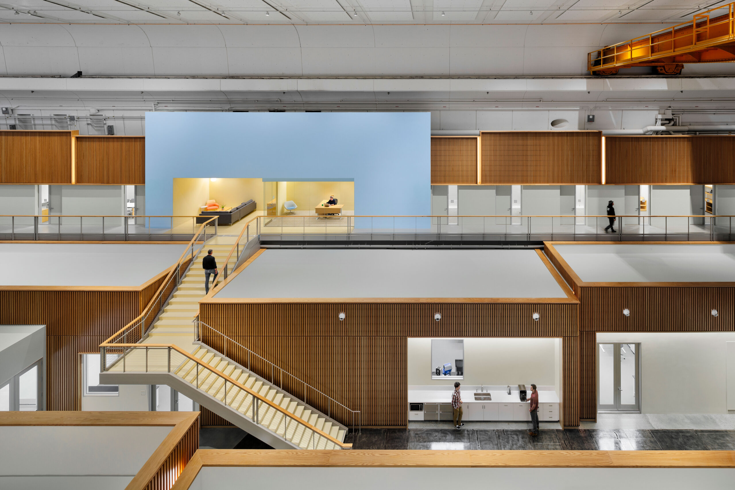 Elevated view of the DEEP Lab's mezzanine level, showing wood-clad laboratories, office spaces, and the original overhead crane preserved from the building's industrial history. A CAS Architects, an FPBA Co. and Jensen Architects education project.