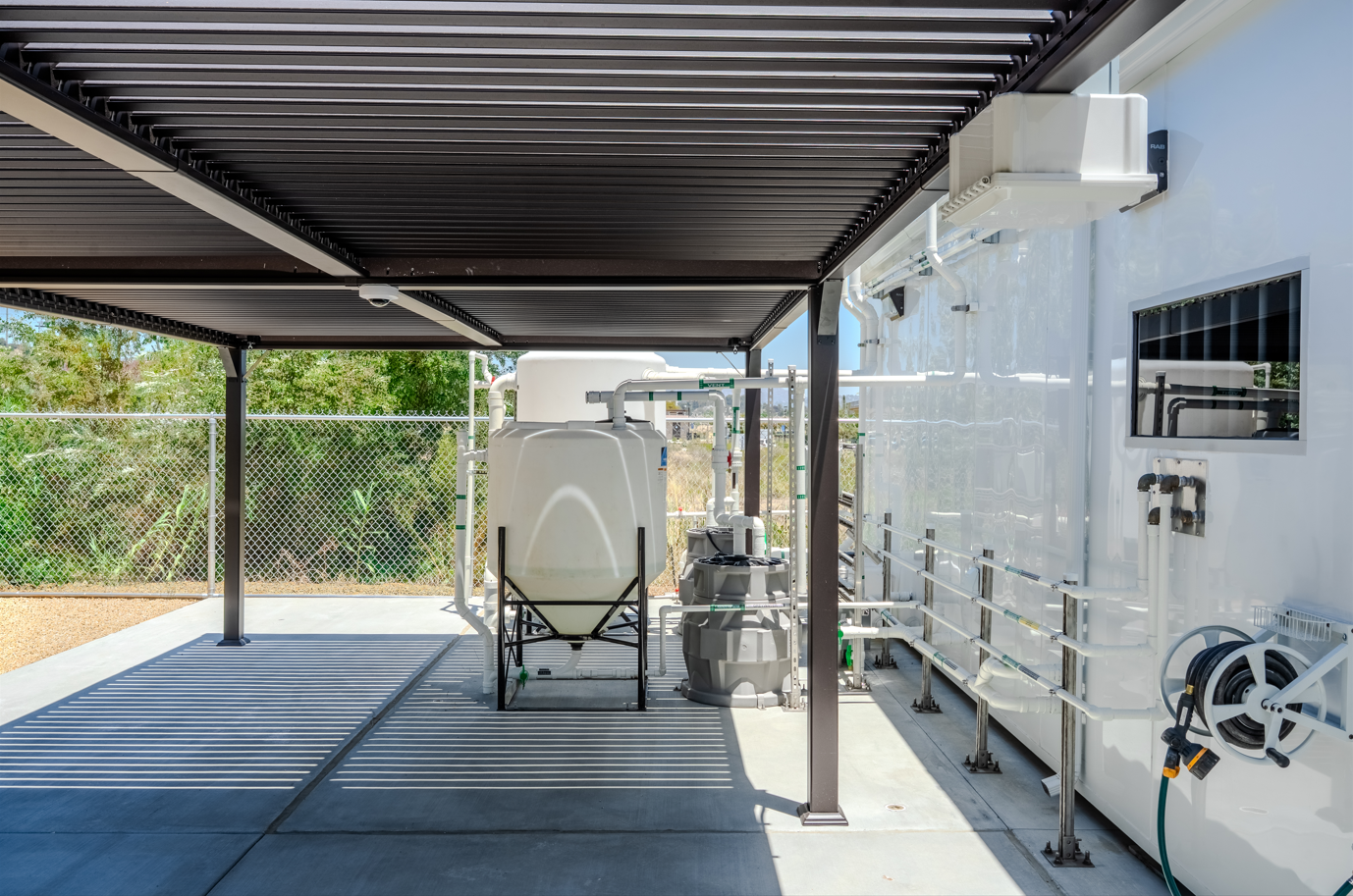Water tanks and piping sit beneath a slatted shade structure outside SDSU's One Water Laboratory, an FPBA higher education project for San Diego State University in Mission Valley.